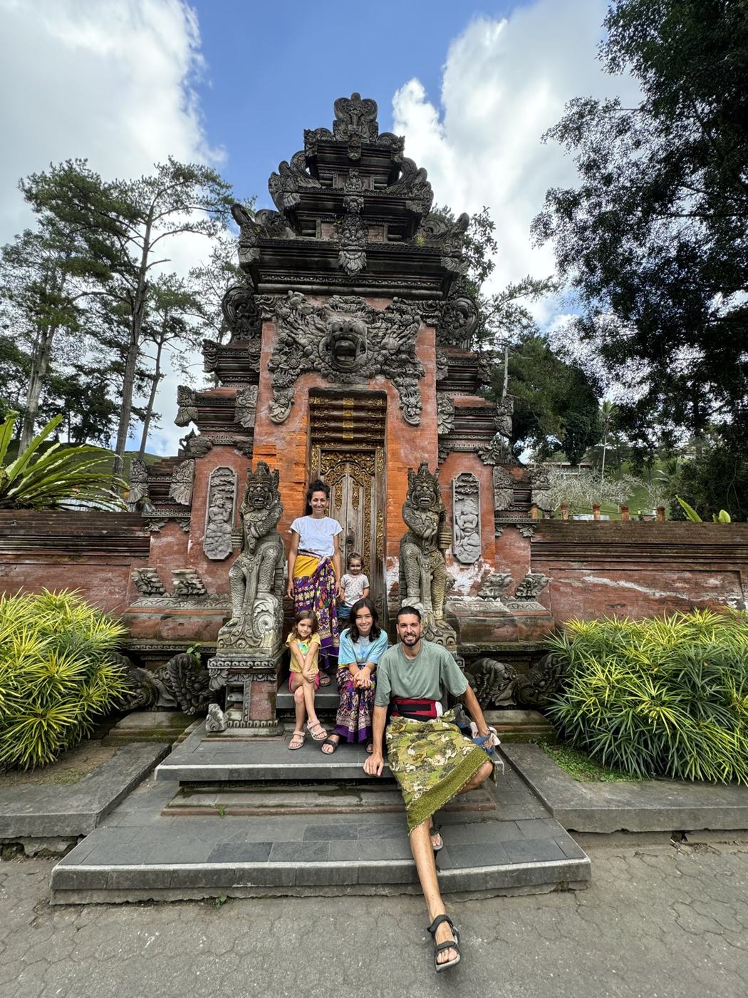 Family sitting on the steps of a carved Balinese temple gate