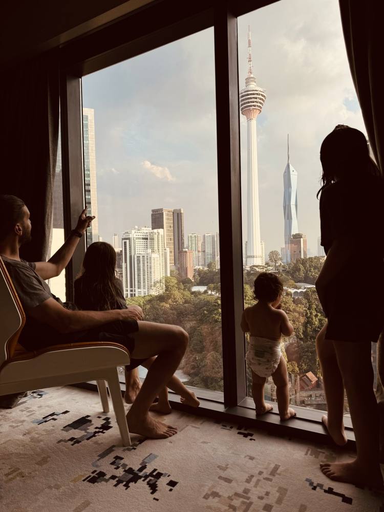 Family at a hotel window looking at the Kuala Lumpur skyline and tower
